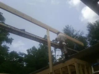 Carpenter setting a ridge beam over a new addition frame — Ice Dam Removal by Roofing Brothers in Constableville