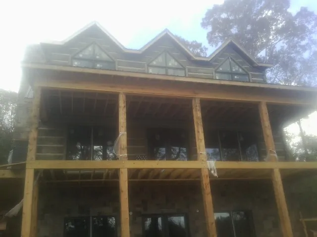 Dormers and porch framing on a large log home under construction — Roof Coating work by our crew in Constableville