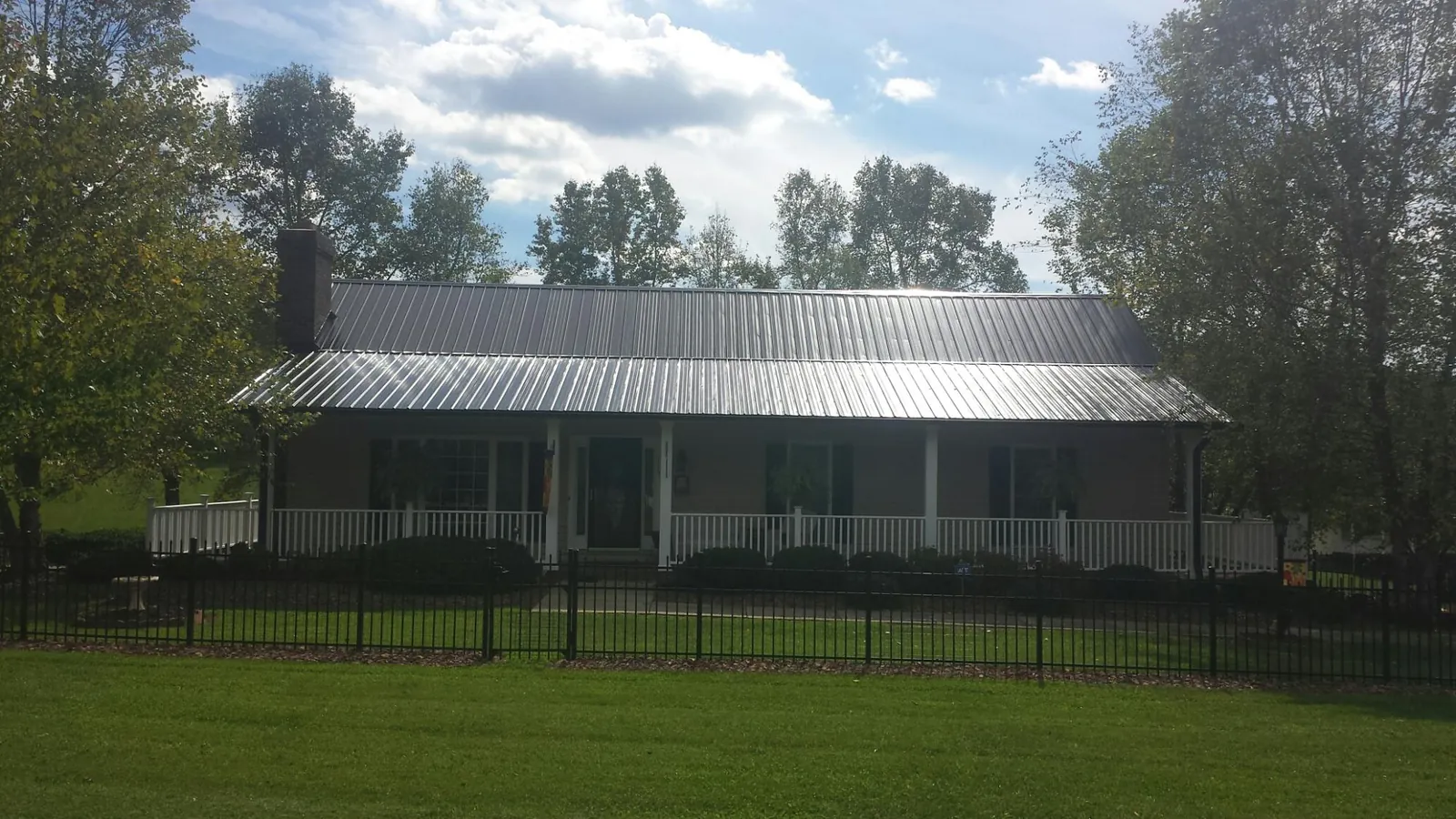 Gray metal roof on a brick ranch with a full width front porch — Gutter Guard Installation work by our crew in Constableville