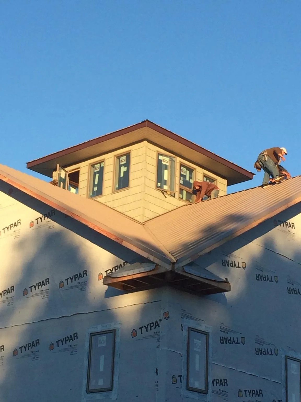 Roofers working around a rooftop cupola on a new metal roof at sunset — Roof Waterproofing in Constableville by Roofing Brothers